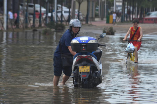 A resident braves waterlog as he travels forward on a flooded road in the urban area of Changsha, capital of central China's Hunan Province, July 5, 2017. (Xinhua/Long Hongtao)