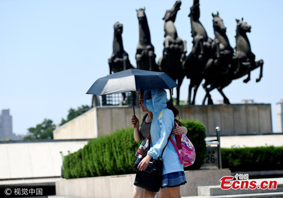 Tourists protect themselves from sunlight in Luoyang City, Henan Province, July 10, 2017. The city has issued an orange alert, with heatwave temperatures at 37 degrees centigrade. (Photo/VCG)