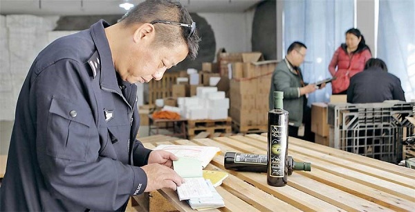 A policeman checks the account books at a warehouse in Qingpu District where expired olive oil was found. (Ti Gong)