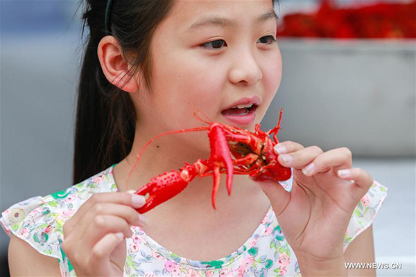 A girl tastes a crayfish during a crayfish festival held in Xuyi county, East China's Jiangsu province, June 12, 2017. (Photo/Xinhua)