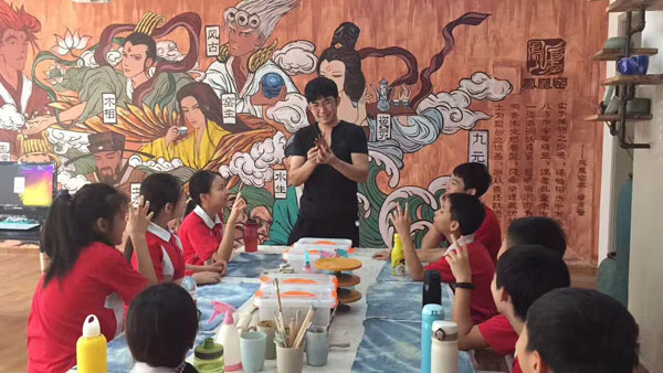 Qu Junmeng shows a class of students how to make miniature ceramic figures.(Photo provided to chinadaily.com.cn)