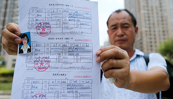 Ma Hongzhou holds the death certificate of his wife, Long Xiuling, in Xi'an, Shaanxi province, on Tuesday. The certificate says Long died of respiratory failure and rabies.(Huang Lijian for China Daily)