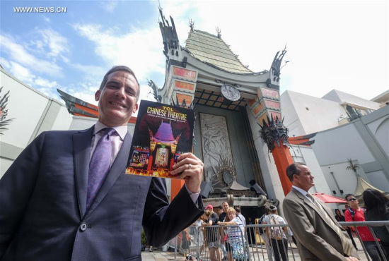 Mayor of Los Angeles Eric Garcetti shows the first commemorative, full-color souvenir book to mark the 90-year history of the TCL Chinese Theatre in Los Angeles, the United States, July 24, 2017. (Xinhua/Zhao Hanrong)