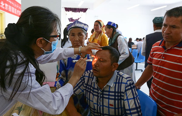 Liu Weihua, an eye doctor from Beijing Tongren Hospital, checks a resident of Hotan, in the Xinjiang Uygur autonomous region, earlier this month.(Xu Zhuzhu/For China Daily)
