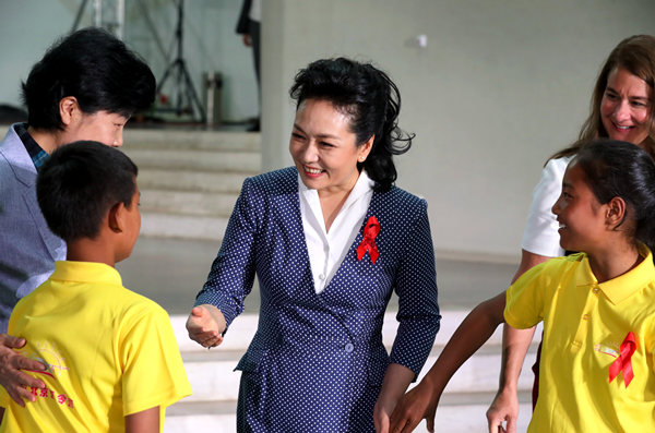 First lady Peng Liyuan greets students at the opening ceremony of the Love in the Sun summer camp in Beijing for youngsters affected by HIV/AIDS. They expressed their appreciation for Peng's longtime support. (PROVIDED TO CHINA DAILY)