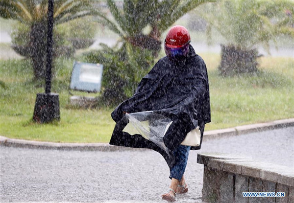 A pedestrian braves heavy rain in Fuqing, Fujian province, on July 31, 2017. Tropical Storm Haitang made landfall in the city on Monday morning in the wake of Typhoon Nesat, which roared into the city on Sunday. The government has warned people about the potential of floods and landslides.(Photo/Xinhua)