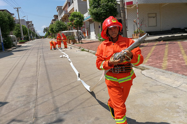 Wu Shuchun carries a firefighting hose at Shantou village, Dadeng Island in East China's Fujian province, on July 24, 2017. (Photo provided to chinadaily.com.cn)