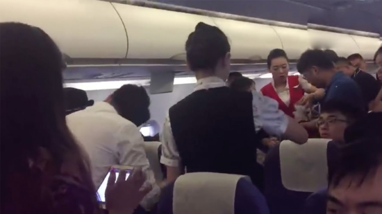Passengers give an aid to a female passenger who passes out due to stuffiness in the cabin. /Screenshot
