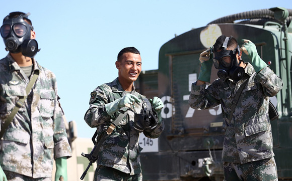Chinese soldiers (from left) Liu Wei, Sodnam Tobgyal and Xue Fanyu prepare for an event that simulates a chemical warfare situation. (Photo: Zou Hong/For China Daily)