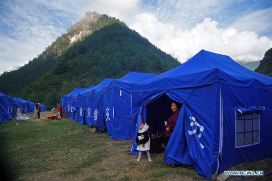 A woman takes a child out of a tent at a temporary shelter in Zhangzha Village of Zhangzha Town in Jiuzhaigou County, southwest China's Sichuan Province, Aug. 11, 2017. (Xinhua/Cai Yang)