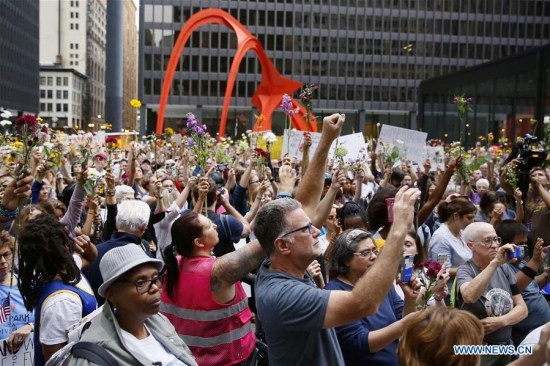 People raise flowers during an evening vigil at Federal Plaza in Chicago, the United States, on Aug. 13, 2017. Several hundred people joined a Sunday evening vigil at Federal Plaza in downtown Chicago, for those who fell victim to the violence in Charlottesville of Virginia during the weekend.(Xinhua/Wang Ping)