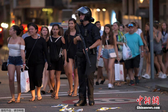 An armed policeman patrols on the street after a white van speeds from the Placa Catalunya down the Las Ramblas thoroughfare in Barcelona's busy tourist area, killing dozens of people. (Photo/Agencies)