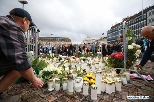 People place candles and flowers to commemorate the victims of Friday's stabbings at the Turku Market Square, Finland on Aug. 19, 2017. Another four Moroccans were detained and a warrant has been issued for a fifth after a young man stabbed people at the squares in the southwestern Finnish city of Turku, police said on Saturday. (Xinhua/Zhang Xuan)