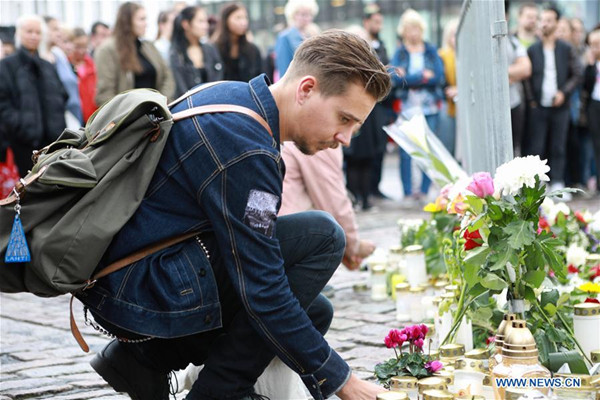 A man places a candle to commemorate the victims of Friday's stabbings at the Turku Market Square, Finland on Aug. 19, 2017. Another four Moroccans were detained and a warrant has been issued for a fifth after a young man stabbed people at the squares in the southwestern Finnish city of Turku, police said on Saturday. (Xinhua/Zhang Xuan)