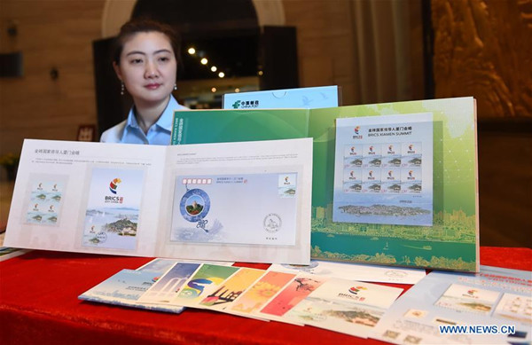 A staff member shows stamps issued by China Post commemorating the BRICS Summit in Xiamen, southeast China's Fujian Province, Aug. 19, 2017. China Post issued a stamp on Saturday to commemorate the BRICS Summit in Xiamen. The stamp bears logo of the summit as well as the letters BRICS and 2017 China. It also shows the scenic Gulangyu island, which was included into the UNESCO list last month, as well as other iconic sites of Xiamen like Xiamen University. (Xinhua/Lin Shanchuan)