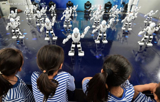 Robots dance as children look on during an exhibition in an amusement park in Handan City of north China's Hebei Province, Aug. 18, 2017. Children in vacation are attracted to learn more about the AI machines. (Xinhua/Hao Qunying)