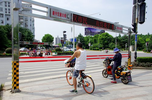 People wait at a new anti-jaywalking gate installed at a major intersection in Wuhan, Central China's Hubei Province. (Photo/China News Service)
