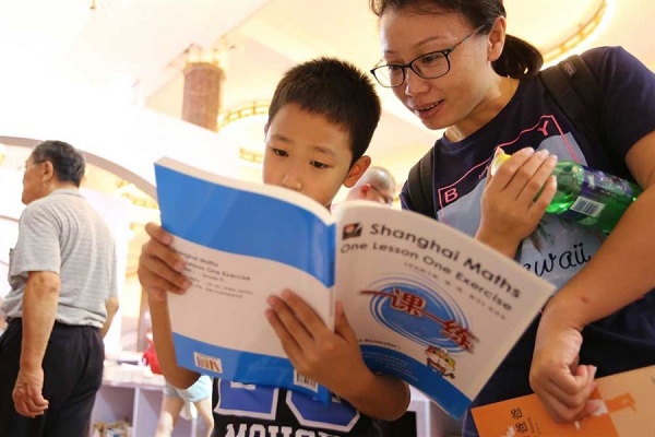 A boy reads attentively the English version of “One Lesson One Exercise” at Shanghai Book Fair where the math textbooks enjoy great popularity. (Wang Ronjiang)