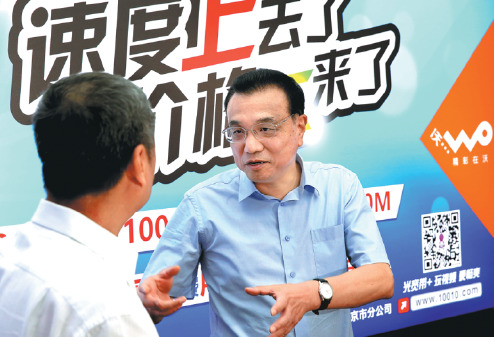 Premier Li Keqiang chats with a China Unicom user at the phone company's headquarters in Beijing on Monday. Li pressed the three largest phone companies earlier this year to make their services more affordable. The board behind Li says of China Unicom's service, "Speed Up, Price Down". (Photo by Wu Zhiyi/China Daily)