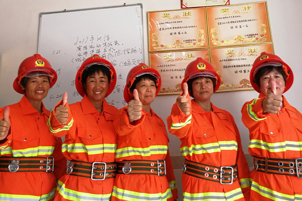 Wu Shuchun, 2nd from right, poses with other brigade members in front of the awards they've won in Shantou village, Dadeng Island in East China's Fujian province, on July 24, 2017. (Photo provided to chinadaily.com.cn)