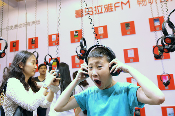A boy listens to an audio program presented by Ximalaya at a fair featuring audio books and user-generated content in Shanghai. (PROVIDED TO CHINA DAILY)