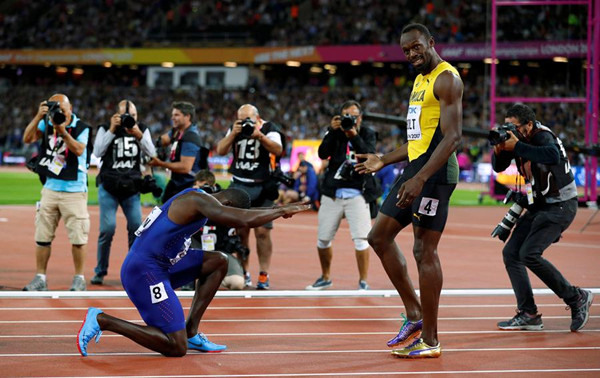 Usain Bolt of Jamaica, right standing, and Justin Gatlin of the US react after their men's 100m final during the World Athletics Championships at the London Stadium, London, Britain, Aug 5, 2017. (Photo/Reuters)