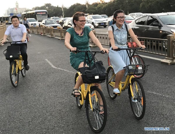 Photo taken by mobile phone shows people riding shared bicycles on Chang'an Avenue in Beijing, capital of China, Aug. 3, 2017. (Xinhua/Luo Xiaoguang)