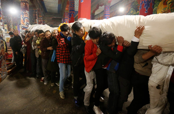 In the morning, monks and believers carry the rolled-up thangka from the monastery on the opening day of Shoton Festival, a traditional annual gala in Lhasa, the Tibet autonomous region. (Photo by Feng Yongbin/China Daily) In the morning, monks and believers carry the rolled-up thangka from the monastery on the opening day of Shoton Festival, a traditional annual gala in Lhasa, the Tibet autonomous region. (Photo by Feng Yongbin/China Daily)