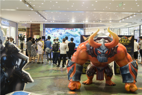 People gather at a department store to watch and play in a King of Glory challenge held by the store in Shanghai. (Photo by Li Sanxian, Yin Ming and Wang Gang/For China Daily)