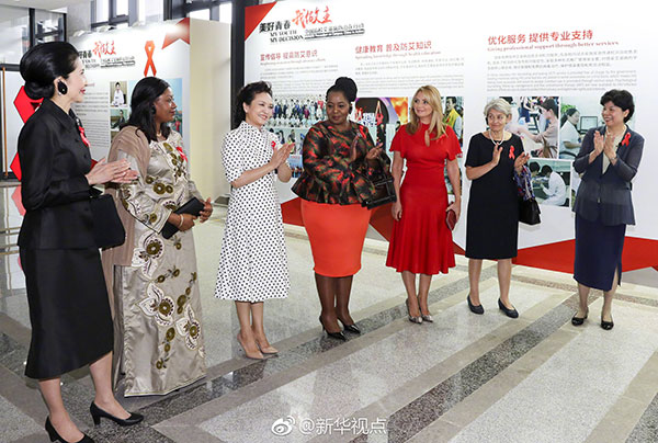 Peng Liyuan, wife of President Xi Jinping, is flanked by a group that includes the wives of leaders of BRICS and other invited countries, as they attend an event to promote HIV/AIDS prevention and control at Xiamen University on Tuesday.(Photo/Xinhua)