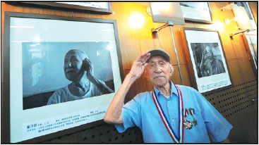 Dong Jimin stands next to a photo of himself at a Beijing exhibition about veterans of the Chinese People's War of Resistance Against Japanese Aggression in August 2015.Provided To China Daily