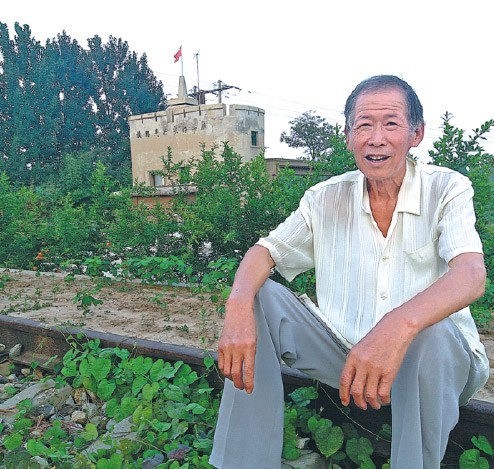 Cao Wentong sits on railway tracks in front of a watchtower built by Japanese troops during the War of Resistance Against Japanese Aggression (1931-45) in Cangxian county, Hebei province. (Photo:China Daily/Lyu Hongyou)