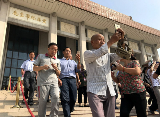 Visitors take photos after leaving the Chairman Mao Memorial Hall in Tian'anmen Square in Beijing on Sept 8, 2017. [Photo by ZOU HONG/CHINA DAILY]
