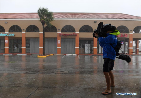 A cameraman takes video among rain and strong winds as hurricane Irma arrives, in Miami, Florida, the United States, on Sept. 10, 2017. Category Four Hurricane Irma on Sunday morning made landfall in the Florida Keys with gust wind speed of 171 km/h, according to the National Hurricane Center (NHC). (Xinhua/Yin Bogu)