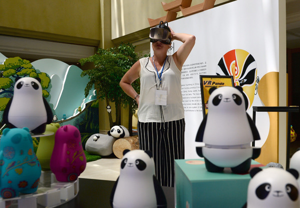 A guest uses virtual reality goggles to view a panda-themed promotional video at the United Nations World Tourism Organization's 22nd General Assembly in Chengdu, Sichuan province, on Monday.(Photo by HAO FEI/CHINA DAILY)