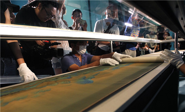 Staff members from the Palace Museum arrange the Song Dynasty masterpiece for the exhibition. (Photo by Zhang Wei/China Daily)