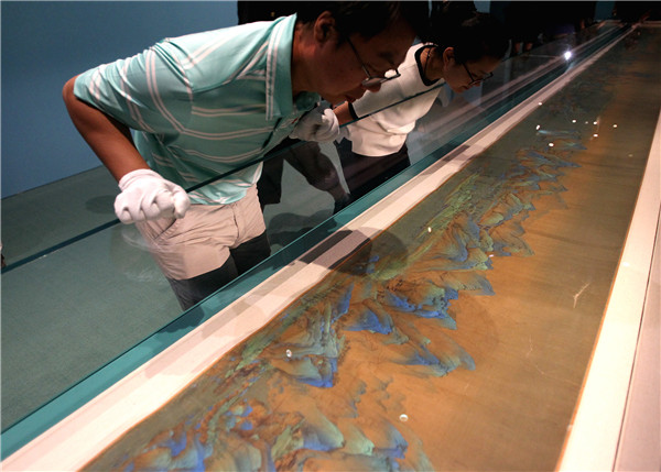 Staff members from the Palace Museum arrange the Song Dynasty masterpiece for the exhibition. (Photo by Zhang Wei/China Daily)