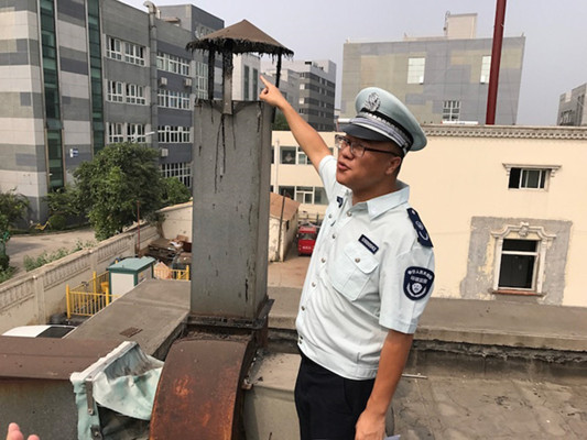 An inspector checks the chimney of a canteen in Beijing last week after an automated monitoring system sent out an alert. The chimney was found without filters.(Photo by QIN SHENGNAN/FOR CHINA DAILY)