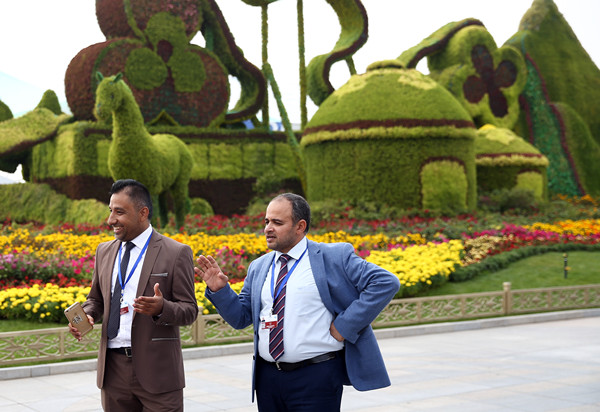 Guests of the 13th Session of the Conference of the Parties to the United Nations Convention to Combat Desertification talk beside a flower bed in Ordos, Inner Mongolia autonomous region. The session concluded in the city on Friday. (ZOU HONG/CHINA DAILY)