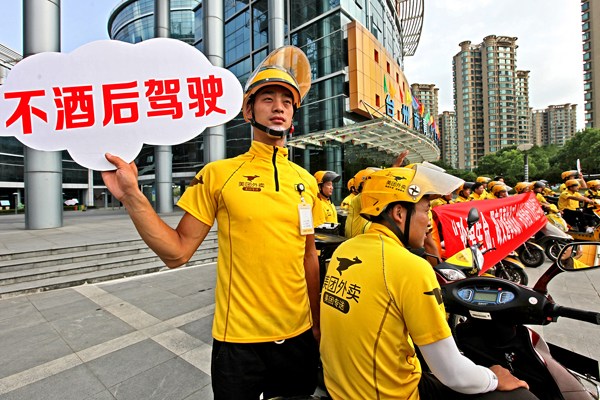 Dozens of food couriers gather in Taizhou, Zhejiang province, earlier this month to affirm their willingness to obey traffic rules. The sign says No drunk driving. Sun Jinbiao/China Daily
