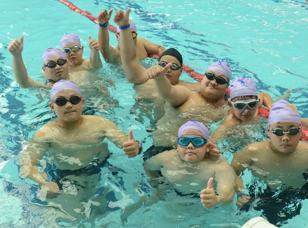 Children prepare for weight-loss swimming workout at a boot camp in Zhengzhou, Henan province. (Photo by ZHANG TAO/CHINA DAILY)