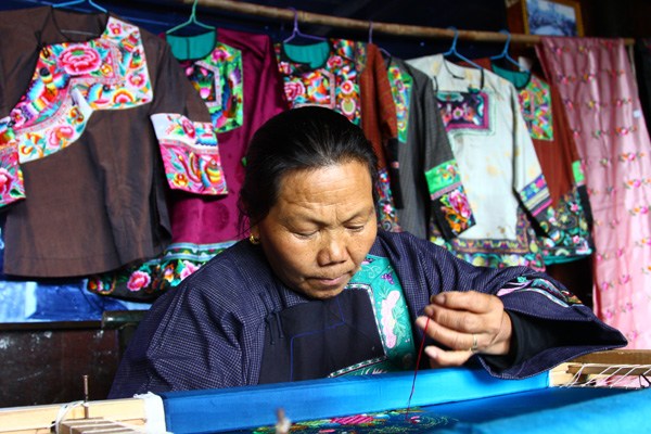 Shi Shunlian of Shibadong village in Hunan province makes Miao embroidery at home. A company helps women market their traditional products for extra income. (Photo by CHEN ZEBING/CHINA DAILY)