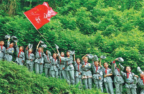 Wearing Red Army uniforms, students from a primary school in Huaying city, Sichuan province, experience the Red Army's Long March by climbing a steep hill. (Qiu Haiying/Xinhua)