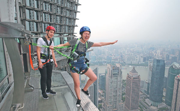 A tourist takes a skywalk at a barrier-free access, which is 340 meters above the ground, at the Jin Mao Tower, an 88-story skyscraper in Shanghai. Gao Erqiang / China Daily