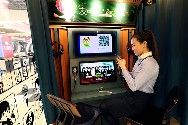 A woman connects her mobile phone with a mini-karaoke system in a shopping mall in Beijing. (FENG YONGBIN/CHINA DAILY)