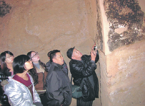 Wang Xiongfei (right) leads his students on a visit of the Kumatula Cave in Xinjiang.(Photo provided to China Daily)