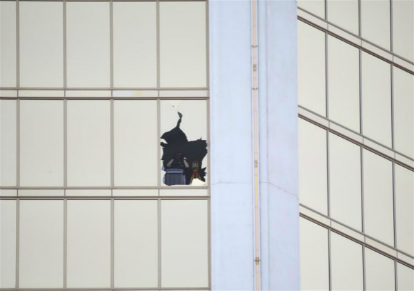 An investigator is seen from one of the broken windows of Mandalay Bay Resort in Las Vegas, the United States, Oct. 4, 2017. (Xinhua/Wang Ying)