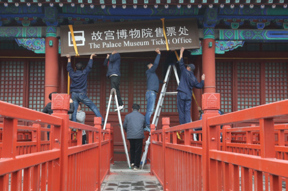 Workers take down a sign at the Palace Museum's ticket office in Beijing on Tuesday. (Photo by Jiang Dong/China Daily)