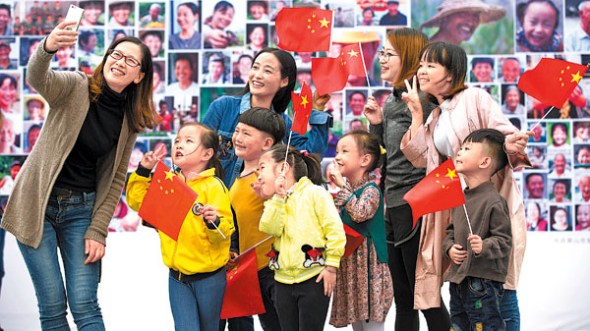 Pupils and teachers pose for a selfie in front of a smiling face wall exhibit in Anhui province on Wednesday. The exhibit, in the former New Fourth Army Memorial Hall, celebrates the 19th Party Congress, starting next Wednesday. (CAO XIAODONG / FOR CHINA DAILY)