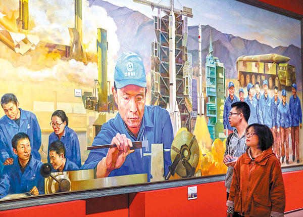 An exhibition celebrating the upcoming 19th National Congress of the Communist Party of China is admired by visitors at the National Museum on Thursday. The painting shows Xu Liping and his team of technicians processing propellant for the nation's ballistic missiles. WANG JING / CHINA DAILY)